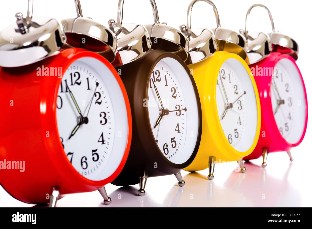 Several brightly colored traditional alarm clocks thrown on a white