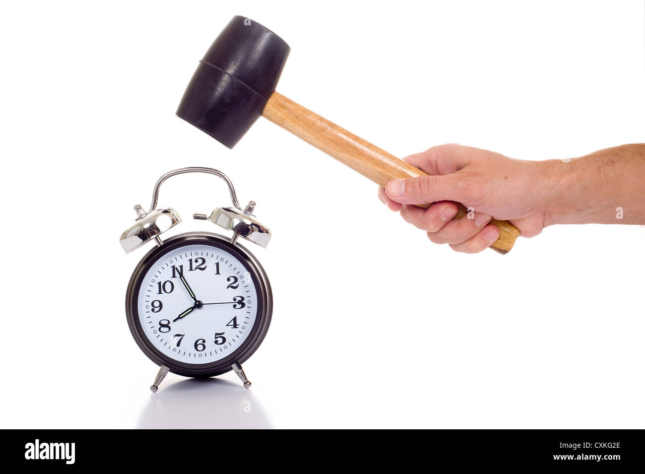 a hand holding a black mallet or hammer about to crush an old fashioned black alarm clock on a white background, time concept Stock Photo