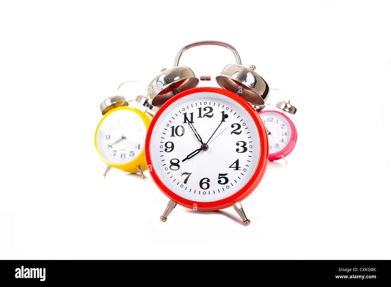 Several brightly colored traditional alarm clocks thrown on a white