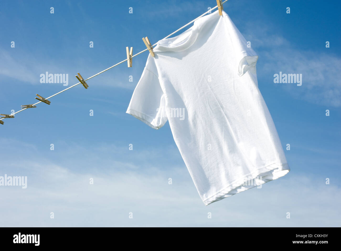 A plain white T-shirt hanging on a clothesline on a beautiful, sunny ...