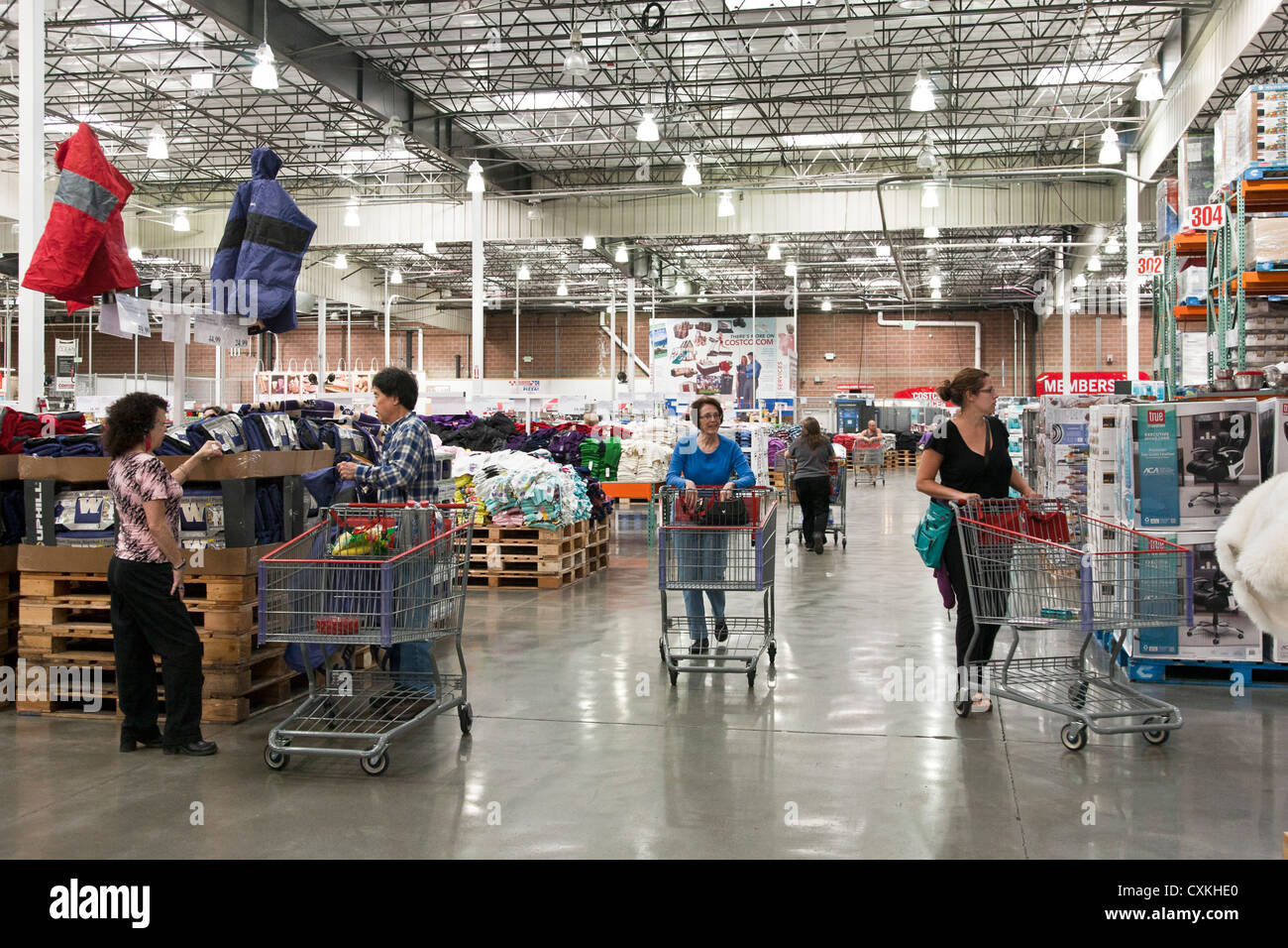 customers with large shopping carts wander clothing & dry goods sections of big box warehouse chain retailer Costco USA Stock Photo