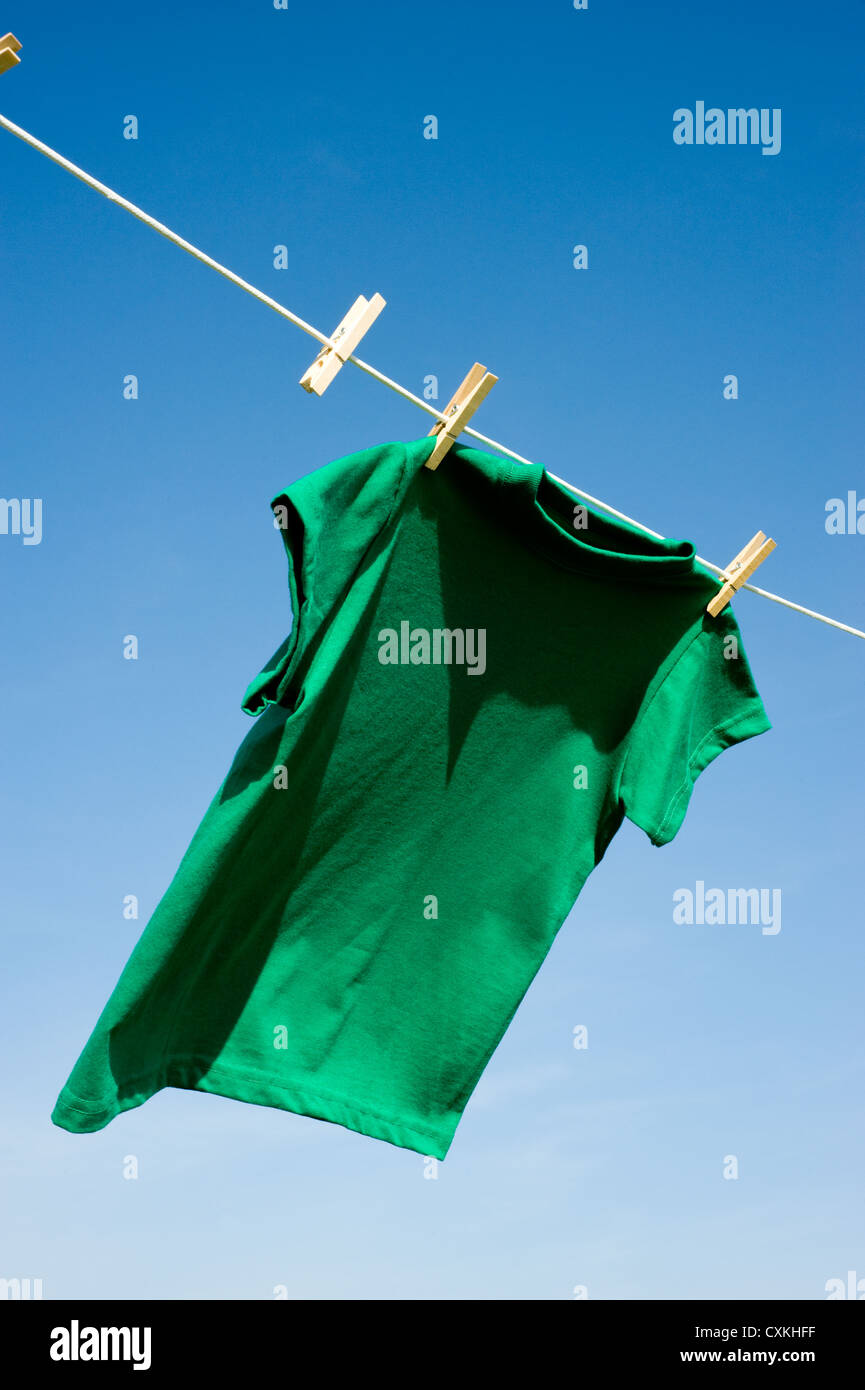 A green colored T-shirts hanging on a clothesline on a beautiful, sunny ...
