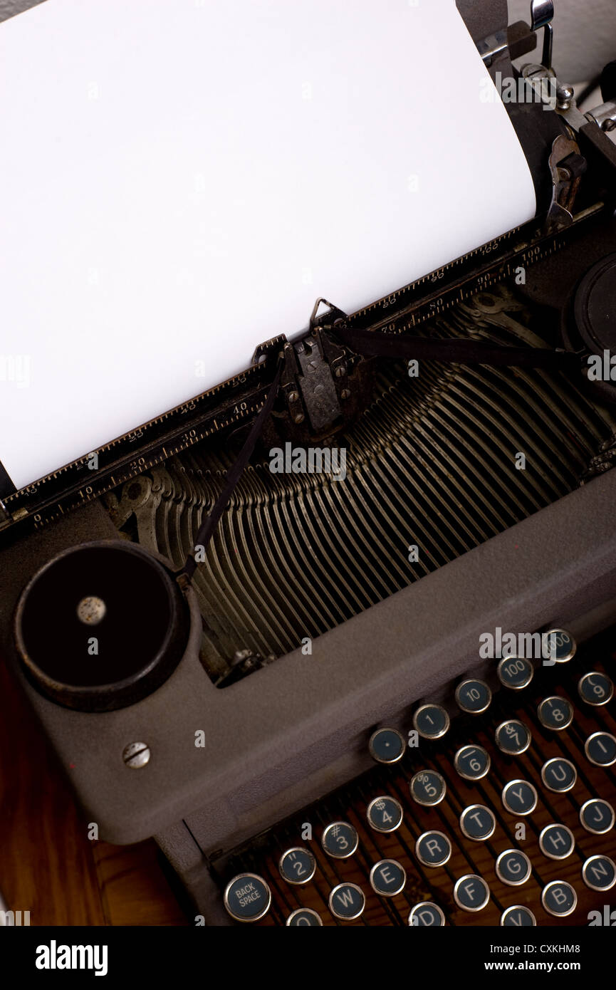 An antique, vintage typewriter with a blank piece of paper for message or copy, image includes keyboard and carriage Stock Photo