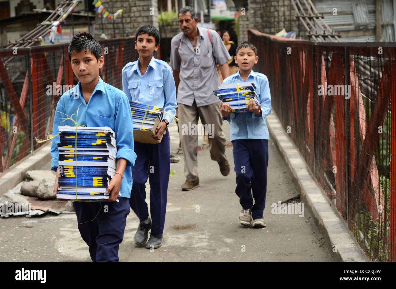 India, Himachal Pradesh, Manikaran, schoolboys bringing books over bridge Stock Photo