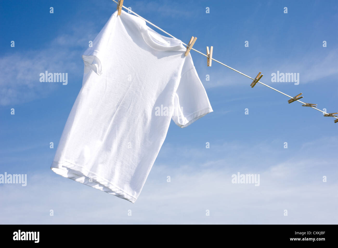A plain white T-shirt hanging on a clothesline on a beautiful, sunny ...