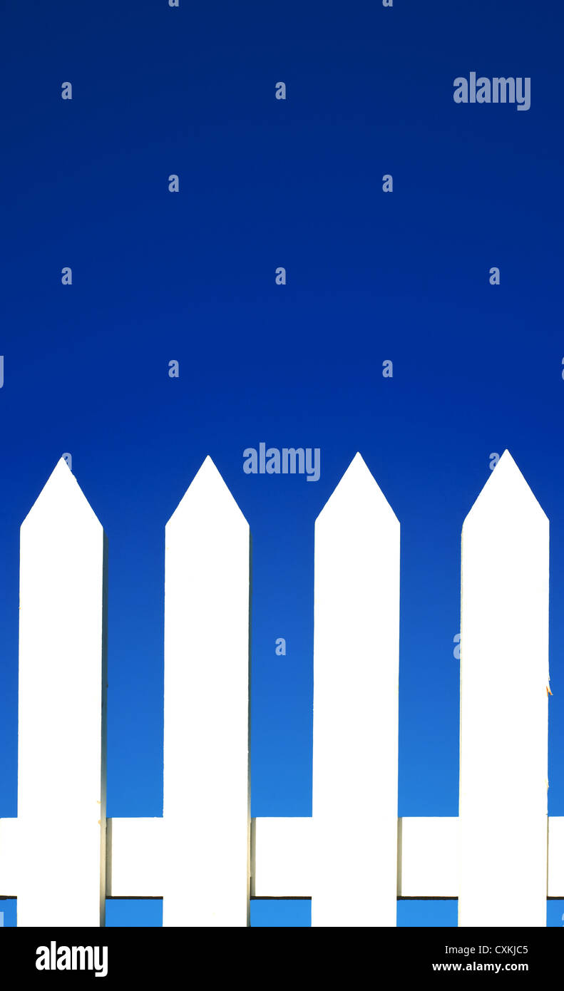 A white picket fence background in front of a bright blue sky with copy ...