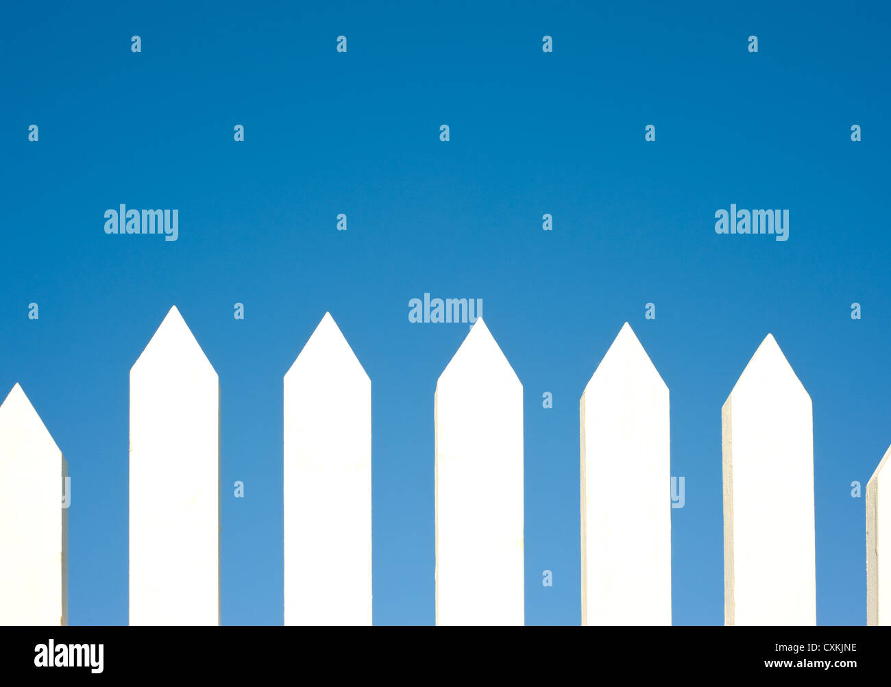 A white picket fence background in front of a bright blue sky with copy ...