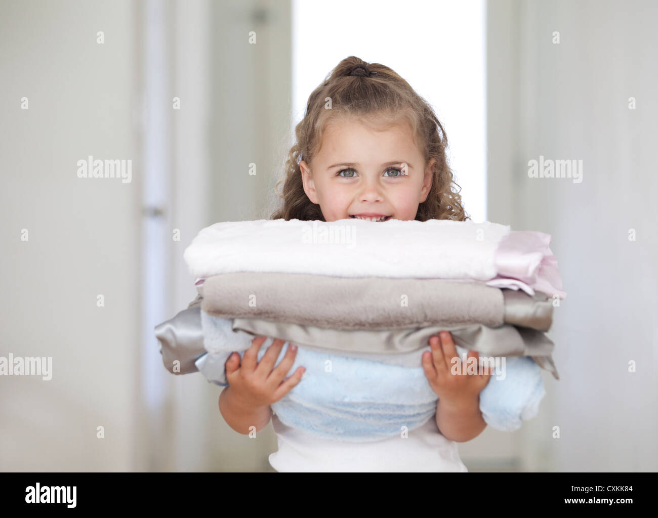 Girl holding stack of blankets Stock Photo Alamy