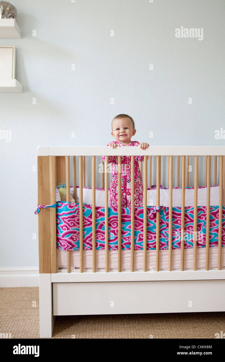 Baby girl standing in crib Stock Photo Alamy