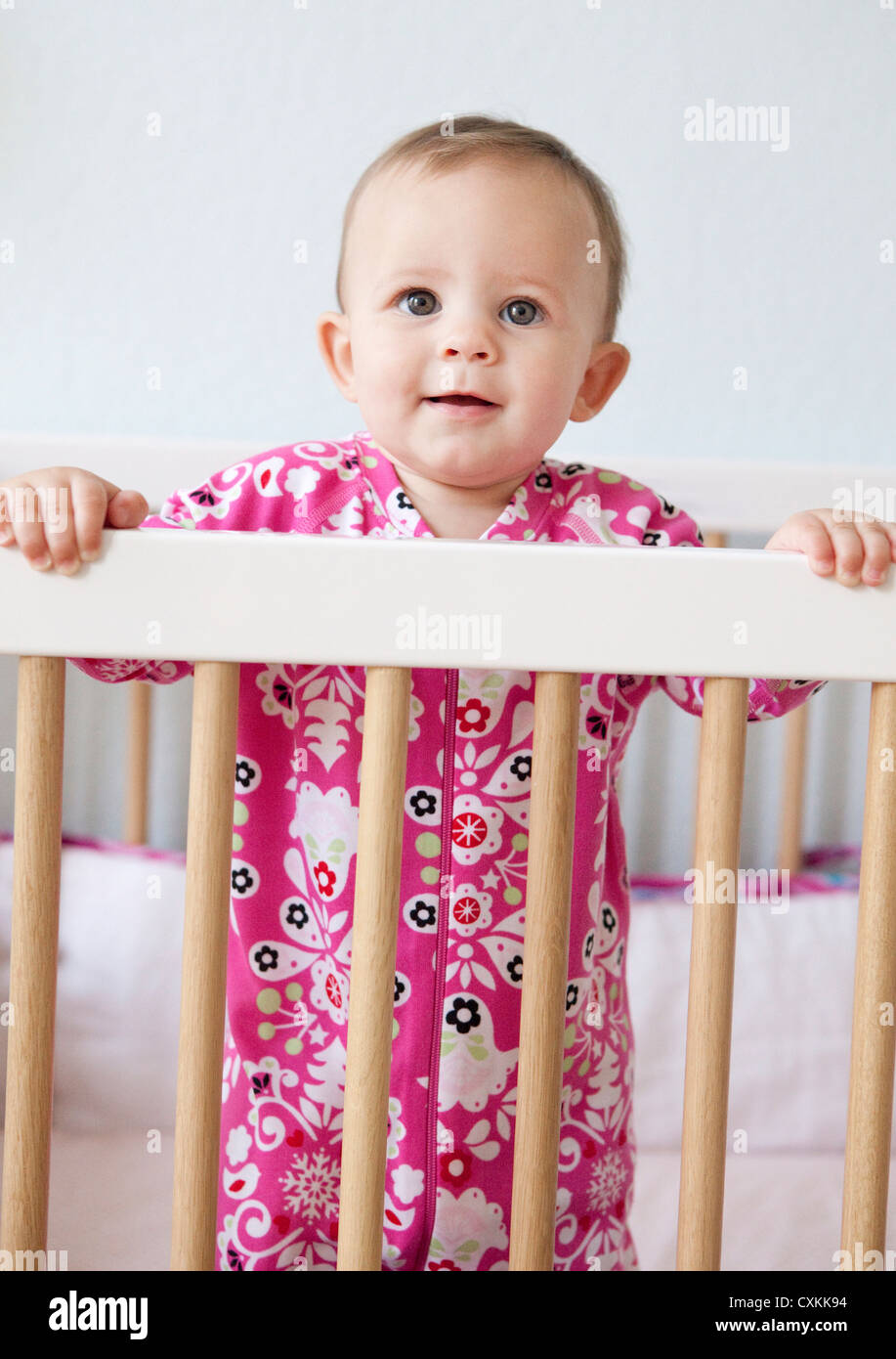 Baby girl standing in crib Stock Photo Alamy