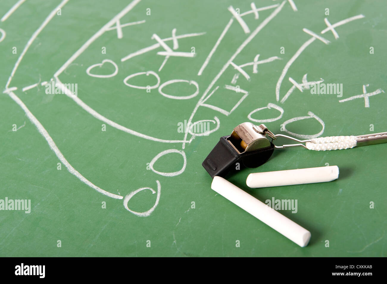 A football play diagram drawn with chalk on a challkboard with chalk and a whistle Stock Photo