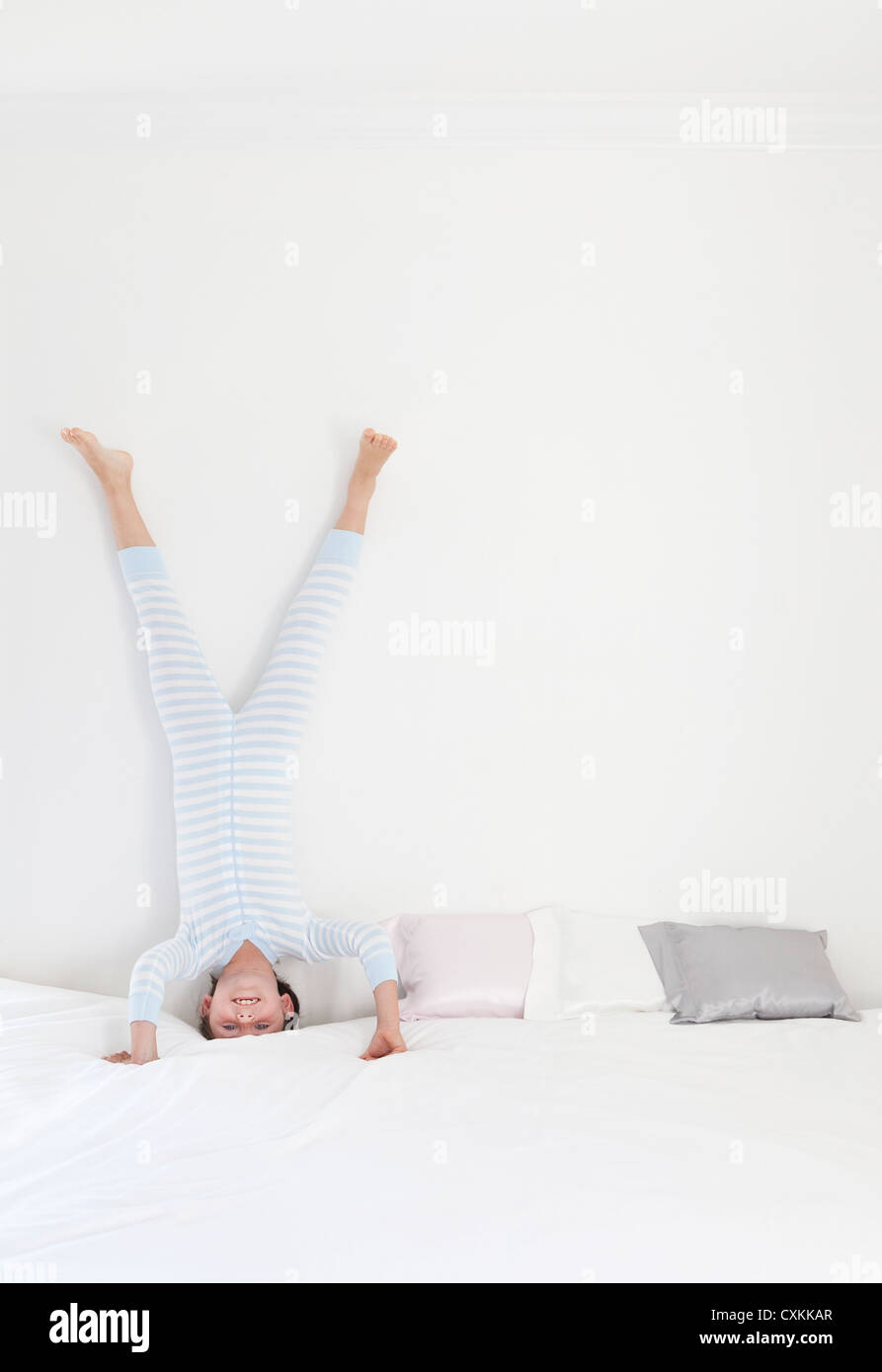 Young girl doing headstand on bed Stock Photo
