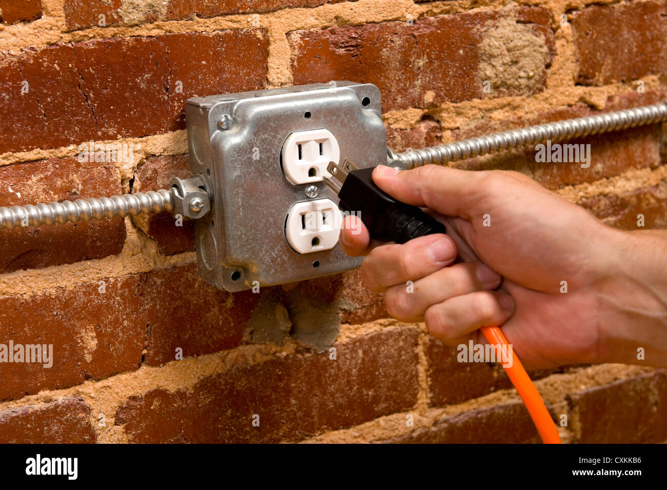 A power cord plugged into a wall power outlet hires stock photography