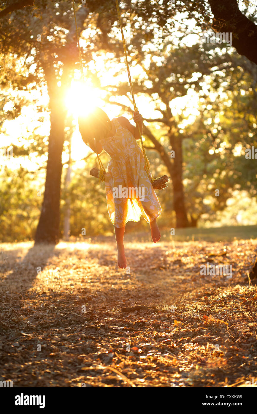 Girl swinging at sunset Stock Photo