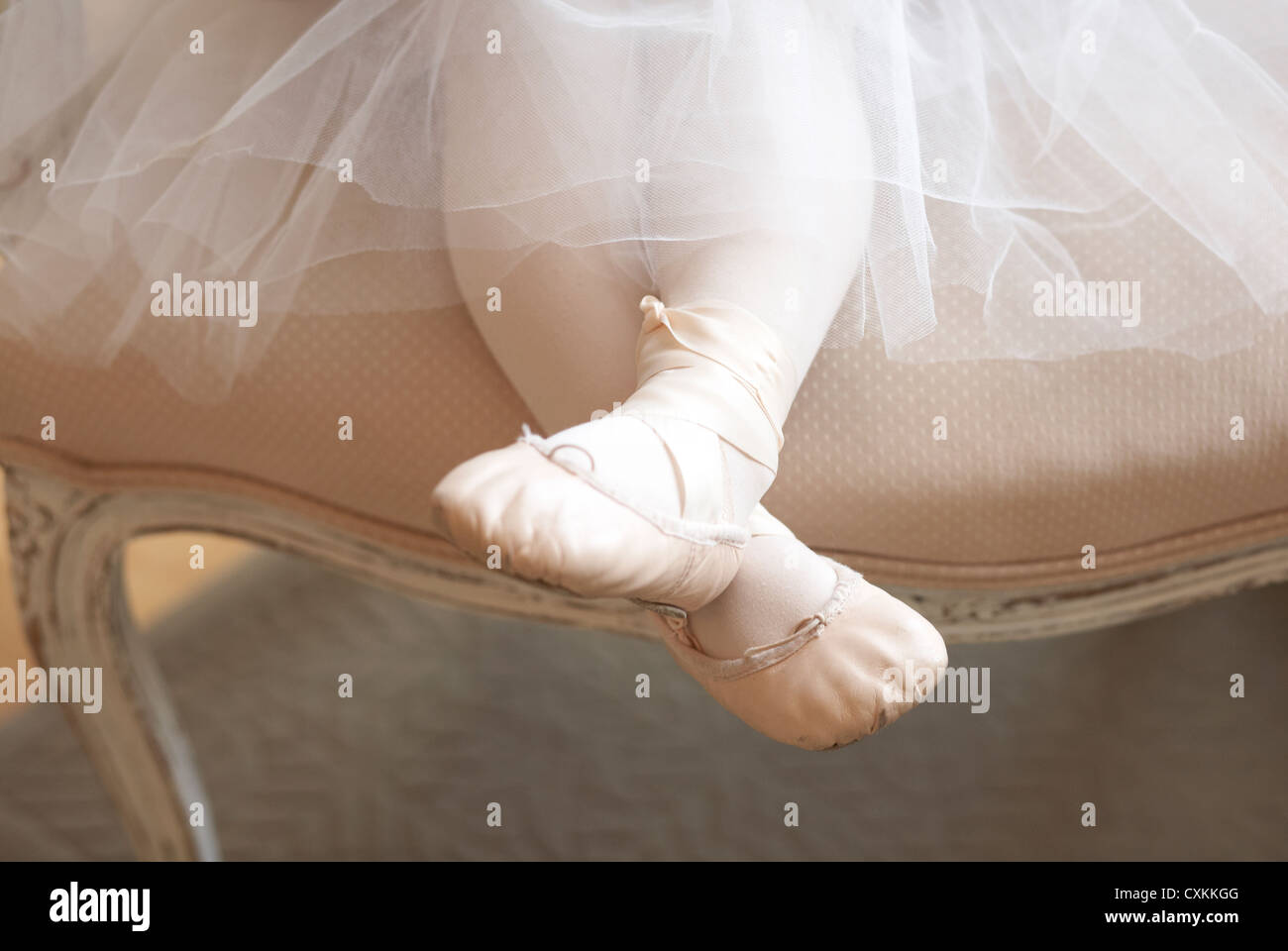 girl in tutu and ballet shoes in a chair Stock Photo