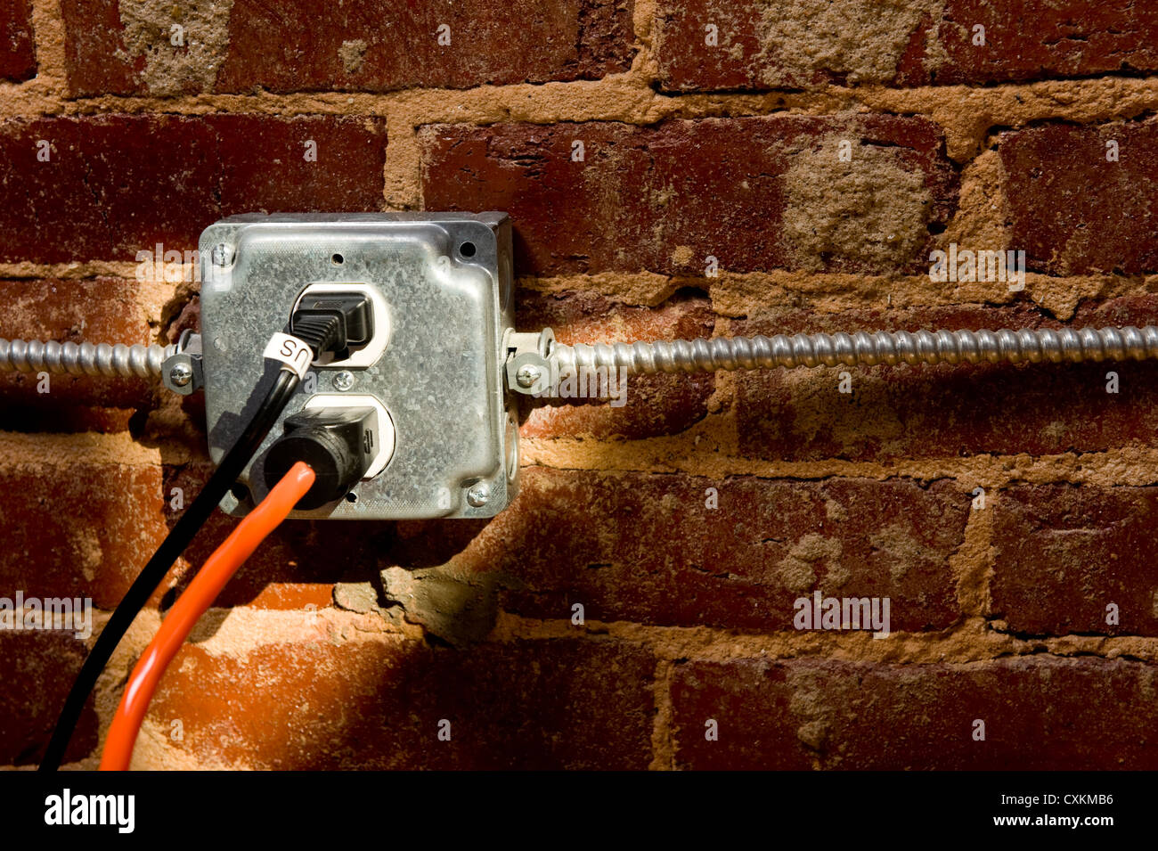 Electrical plug on a brick wall with a cord or extension cord plugged in, concept of connecting