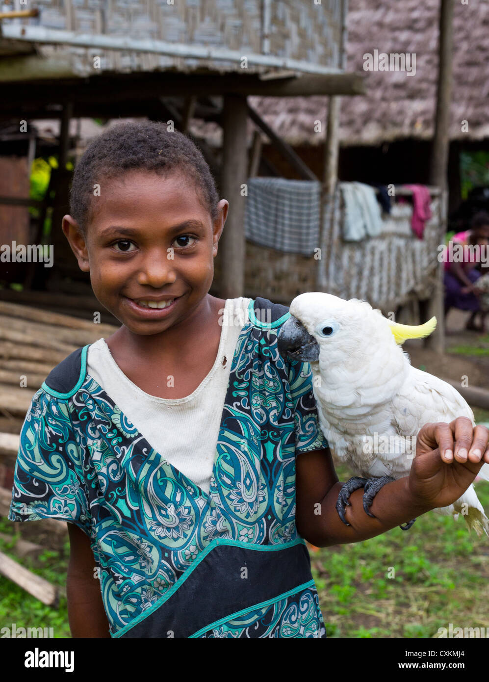 Young village girl smiling and holding a Triton Cockatoo (Cacatua galerita triton) , Erap valley, Papua New Guinea Stock Photo