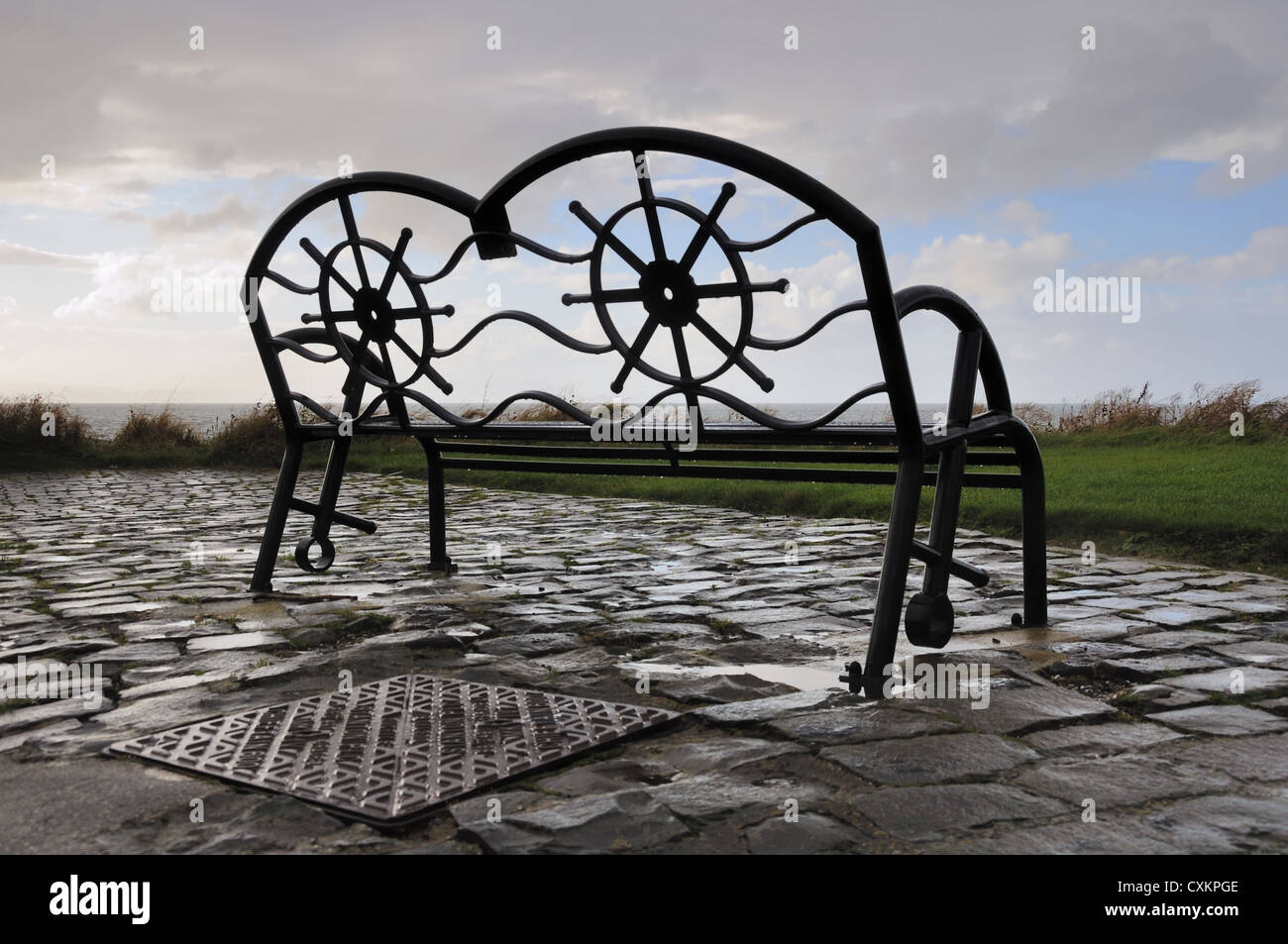 A metal bench fabricated on a nautical theme overlooks the ocean. Stock Photo