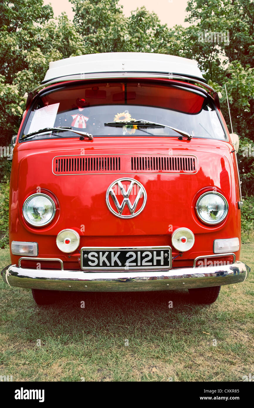 Front view of red vintage VW camper van parked on grass Stock Photo