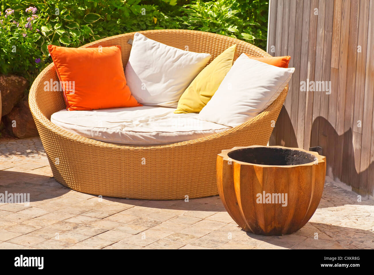 A modern wicker garden sofa or love seat in the home garden. Stock Photo