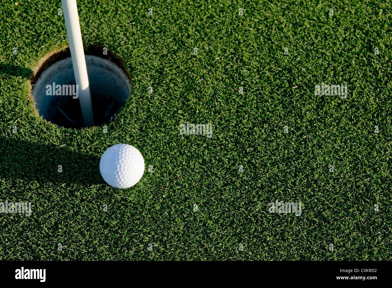 A white golf ball near the hole of a golfing green or course Stock Photo