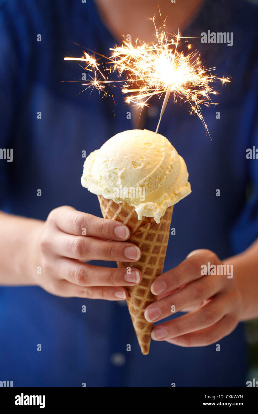 Woman Holding Vanilla Ice Cream Cone with Sparkler Stock Photo