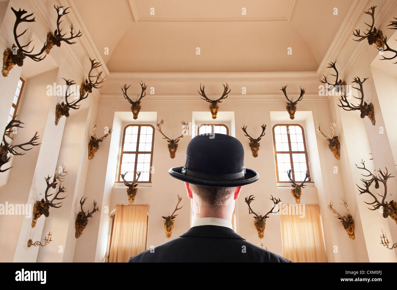 man facing a room filled with elk head trophy's Stock Photo