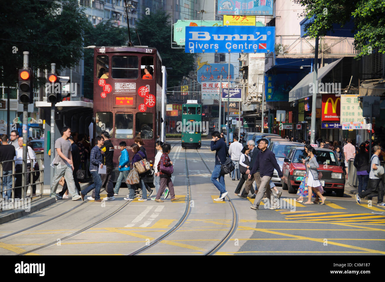Pedestrians cross the tram tracks on Johnston Road in the Wan Chai district of Hong Kong Island Stock Photo