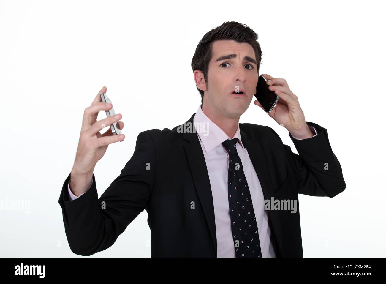 Overwhelmed businessman answering telephones Stock Photo