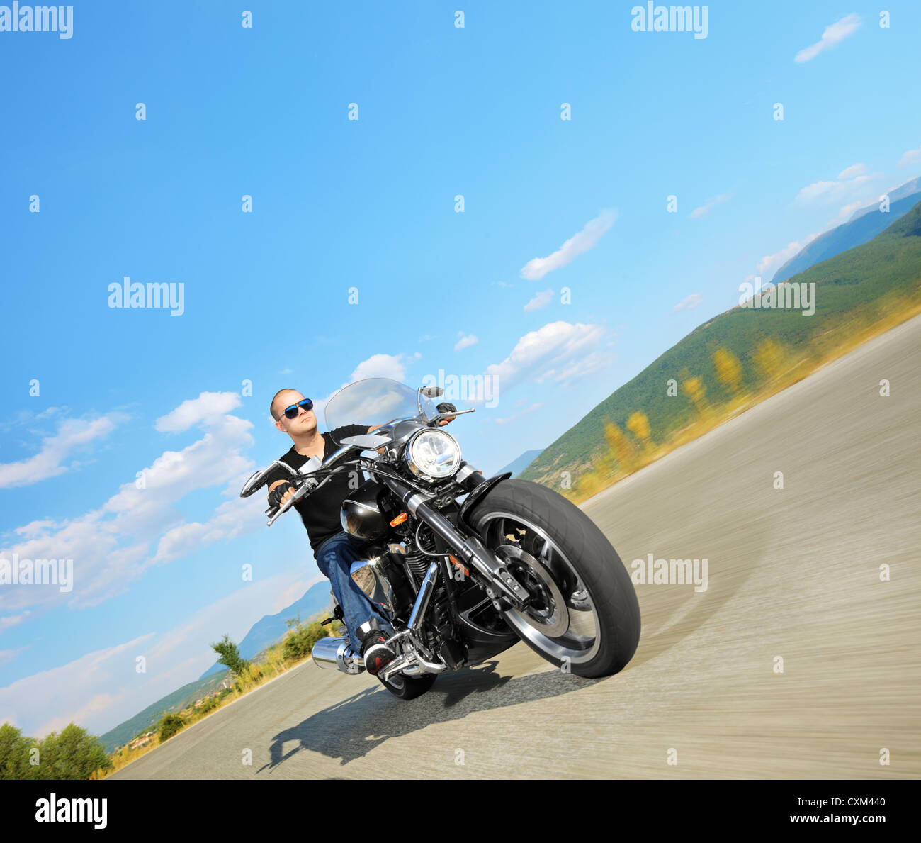 Biker riding a customized motorcycle on an open road Stock Photo