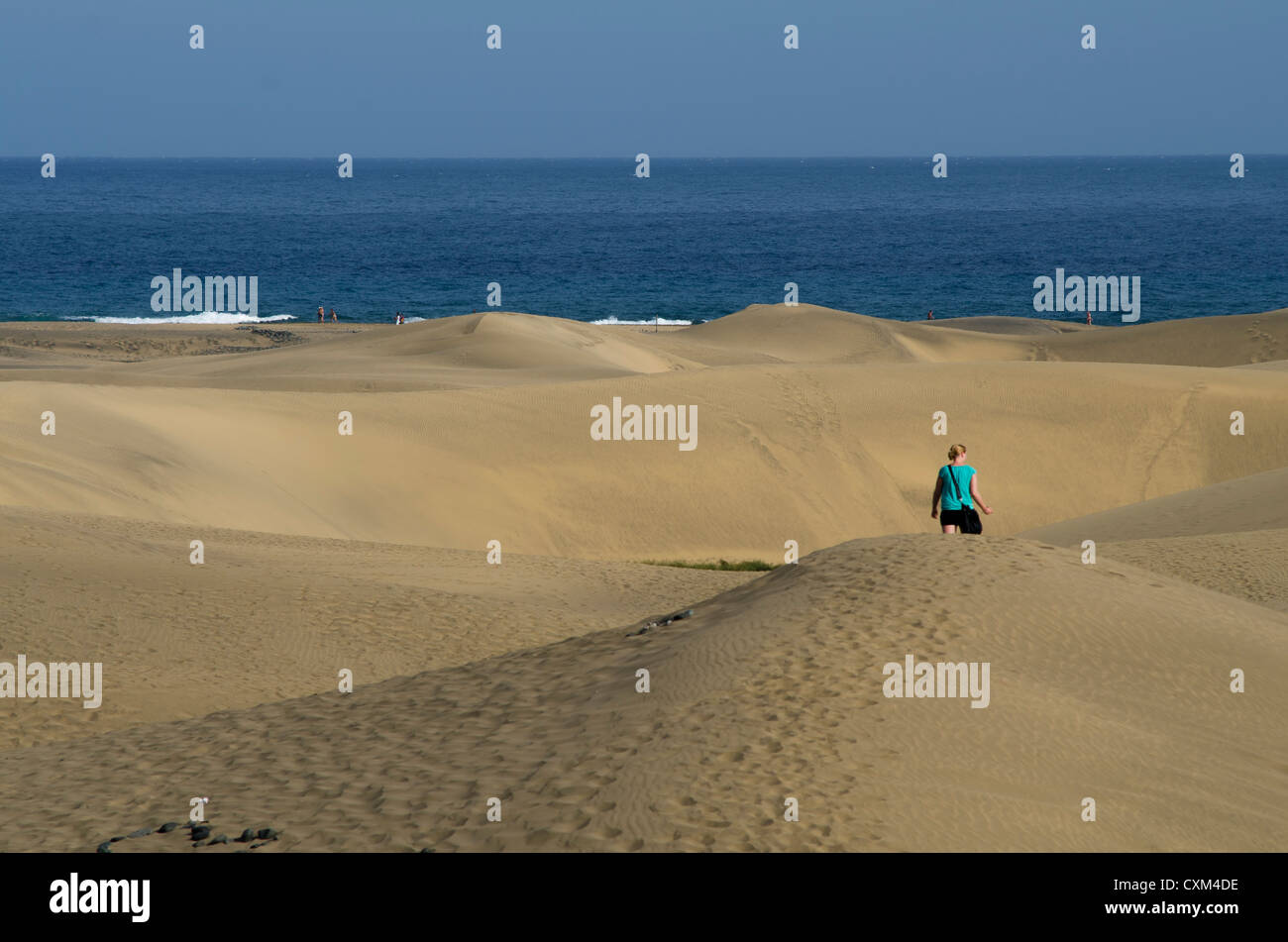 woman walking towards the sea in the dunes of maspalomas Gran Canaria Canary Island Spain Stock Photo