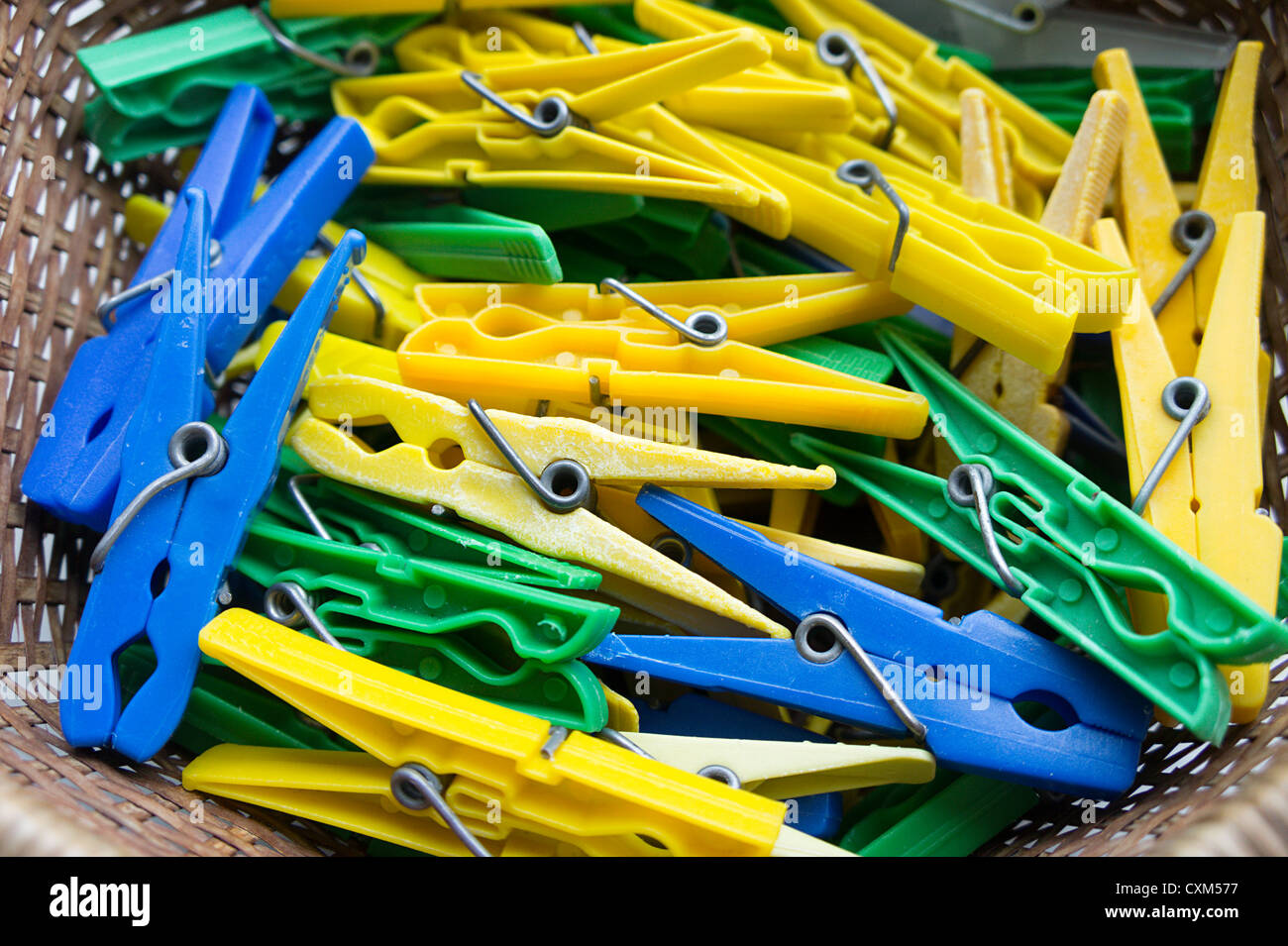 Pile of yellow, blue and green plastic clothes pegs Stock Photo
