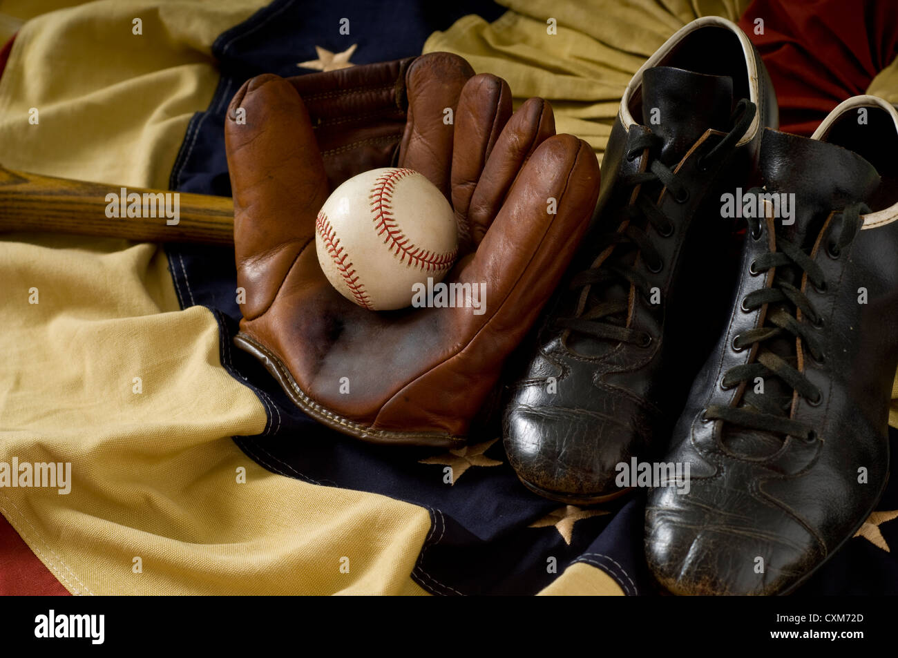 Vintage baseball equipment including Mitt, ball, cleats and a ball on an antique flag as background Stock Photo