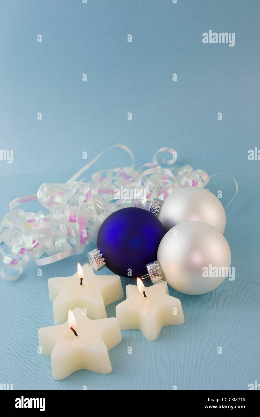 three Christmas star shaped candles, blue and white ornaments on a soft blue background with copyspace Stock Photo
