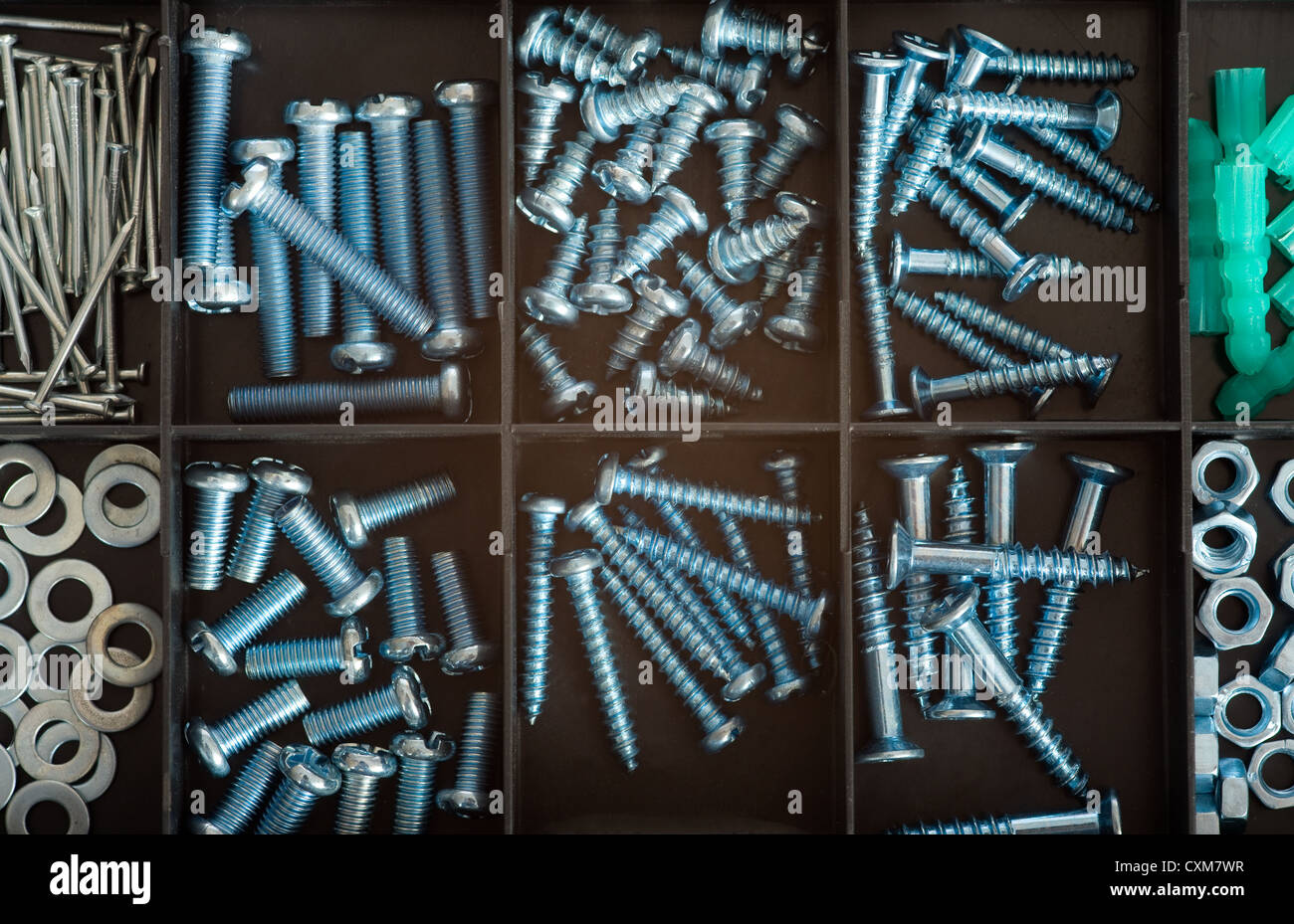 A background of a variety of fasteners including screws and nails is a small black box Stock Photo
