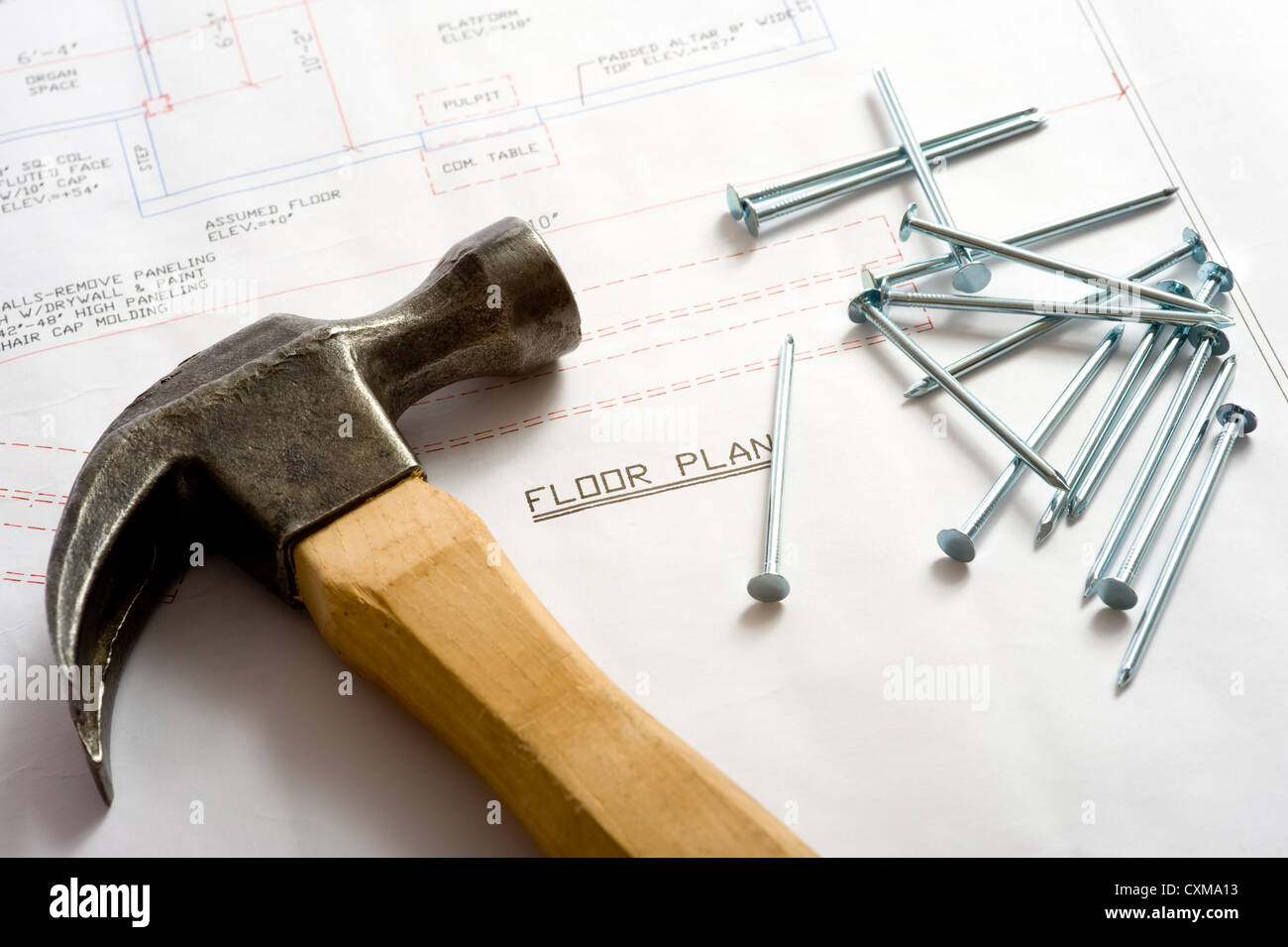 A hammer and nails lying on top of a house floor plan or blue print
