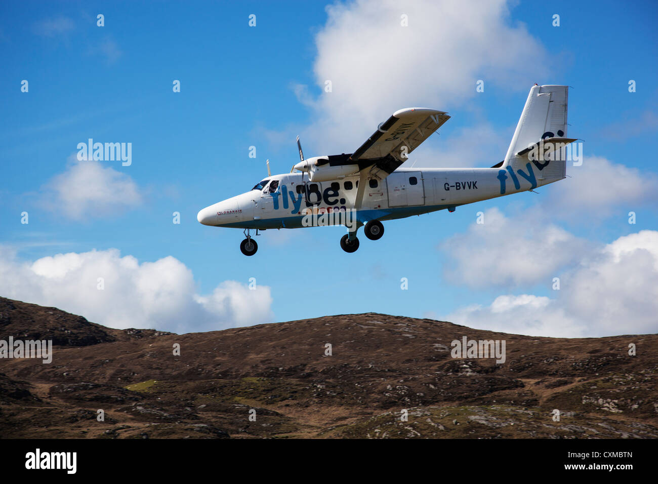 A small passenger plane comes in to land above the sand dunes at Barra Airport, Outer Hebrides, Scotland, UK Stock Photo