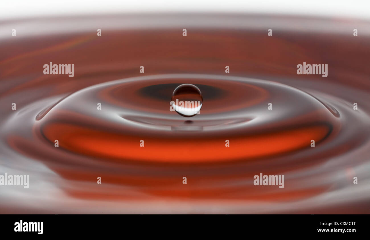 a water drop suspended in a splash in red Stock Photo Alamy