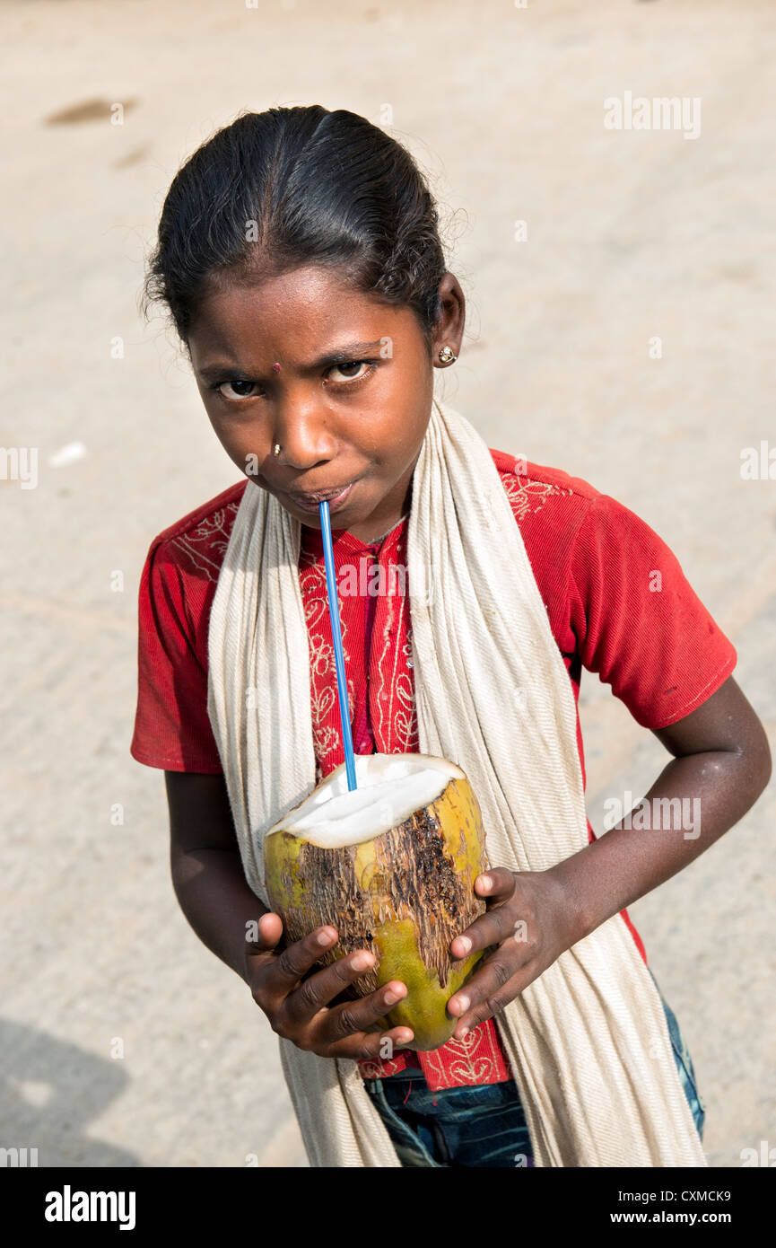 Happy young Indian street girl drinking coconut water from the coconut