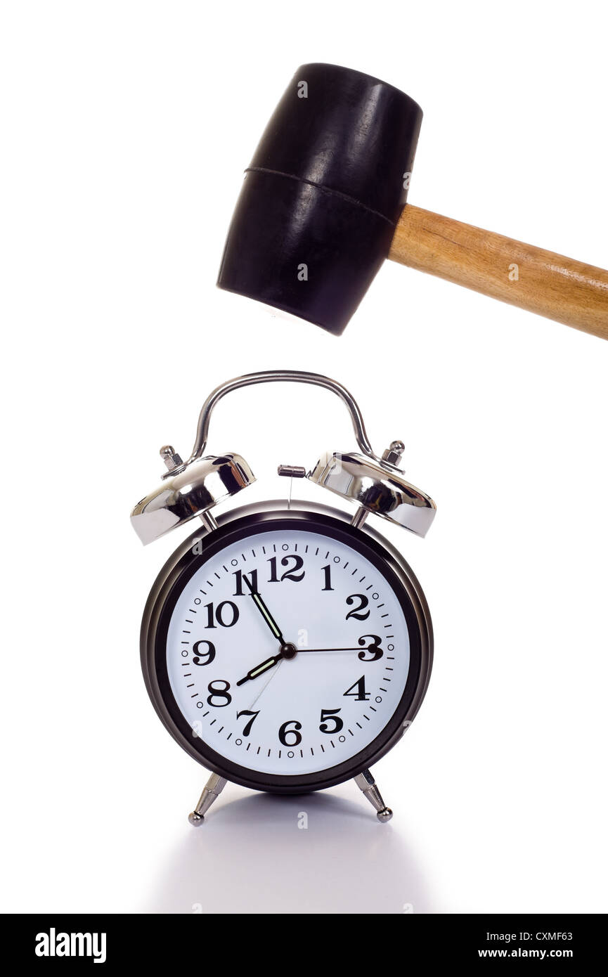 a hand holding a black mallet or hammer about to crush an old fashioned alarm clock on a white background, time concept Stock Photo