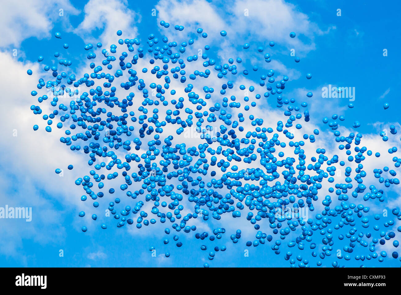 Blue balloons high in the blue sky against white clouds Stock Photo