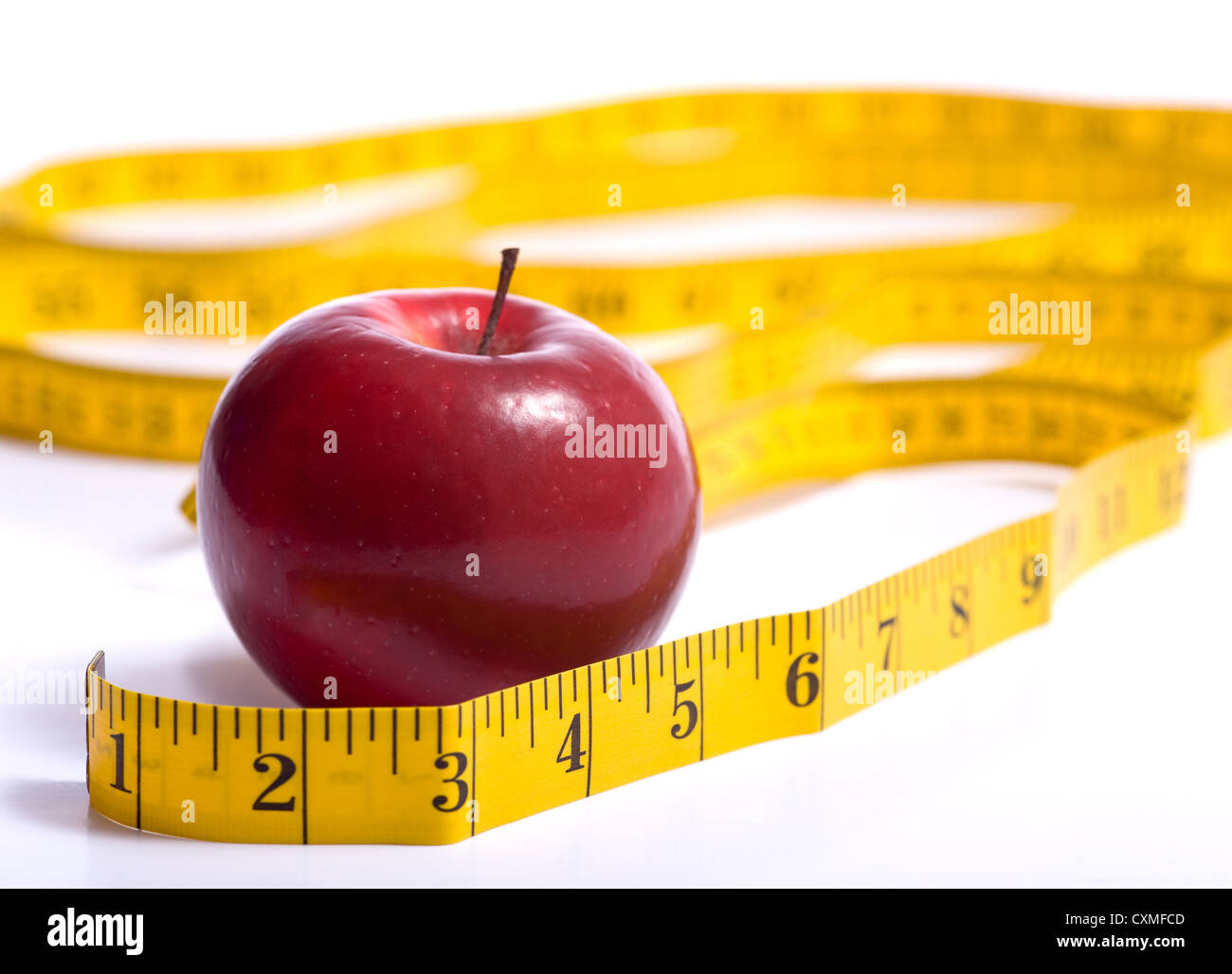 A red apple and a yellow tape measure on a white background. Dieting or healthy eating concept. Stock Photo