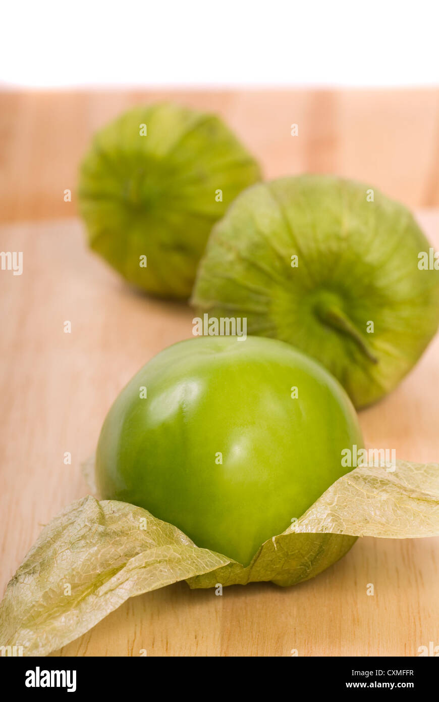 Three fresh tomatillos on a cutting board Stock Photo