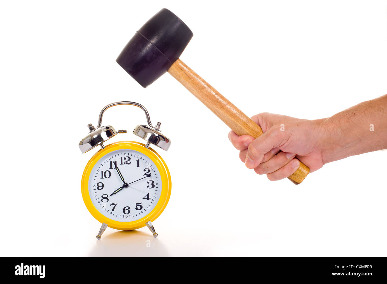 a hand holding a black mallet or hammer about to crush an old fashioned yellow alarm clock on a white background, time concept Stock Photo