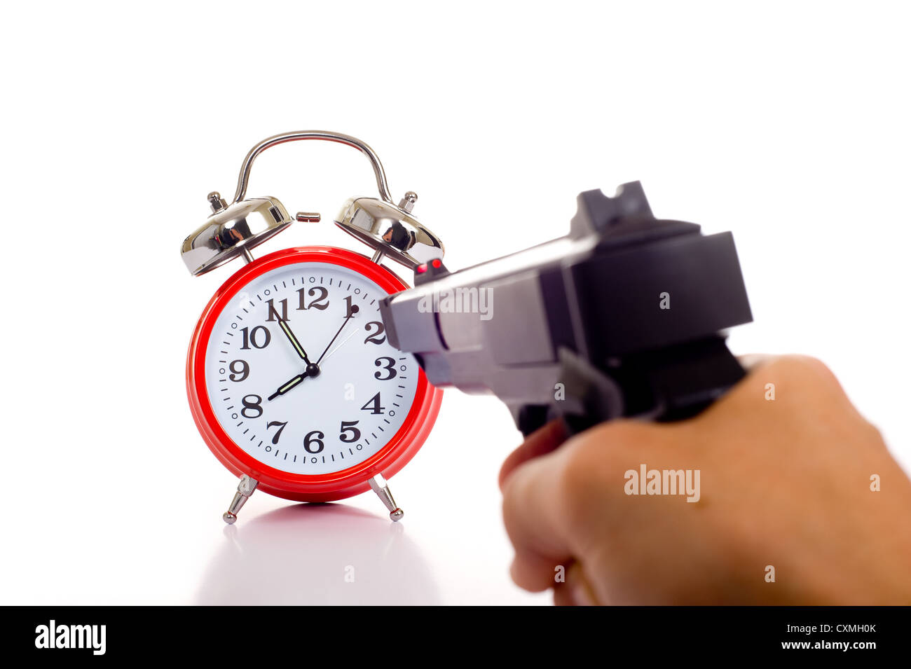A hand holding a gun aimed at a red vintage alarm clock Stock Photo - Alamy