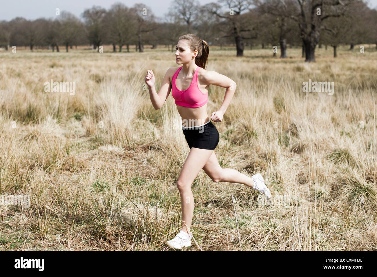Woman runner running through a park Stock Photo