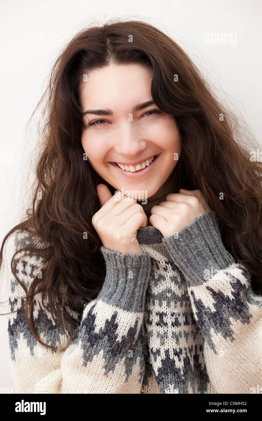 Beautiful brunette girl in the studio smiling at the camera and wearing a warm patterned woolly winter sweater Stock Photo