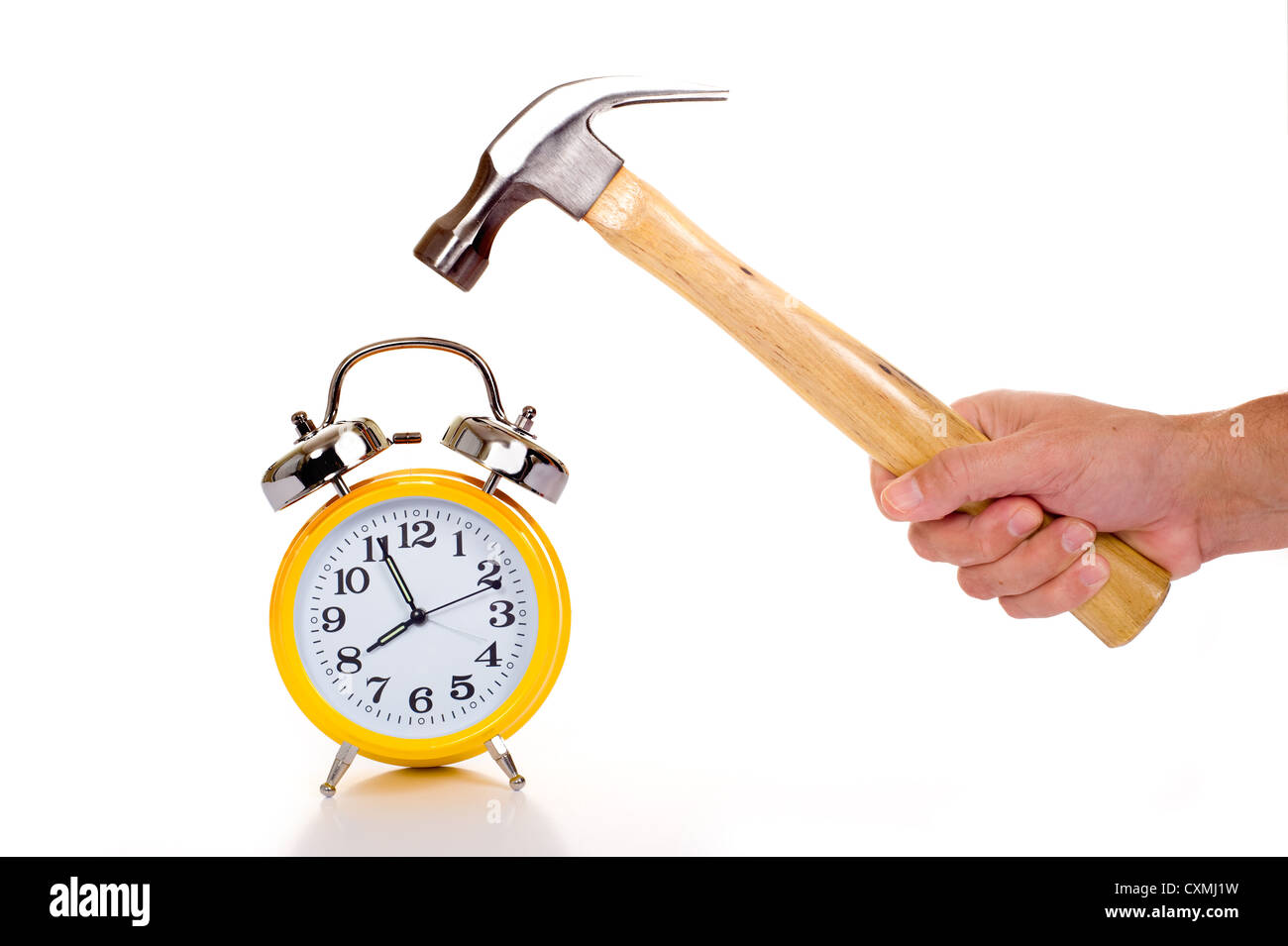 a hand holding a black mallet or hammer about to crush an old fashioned yellow alarm clock on a white background, time concept Stock Photo