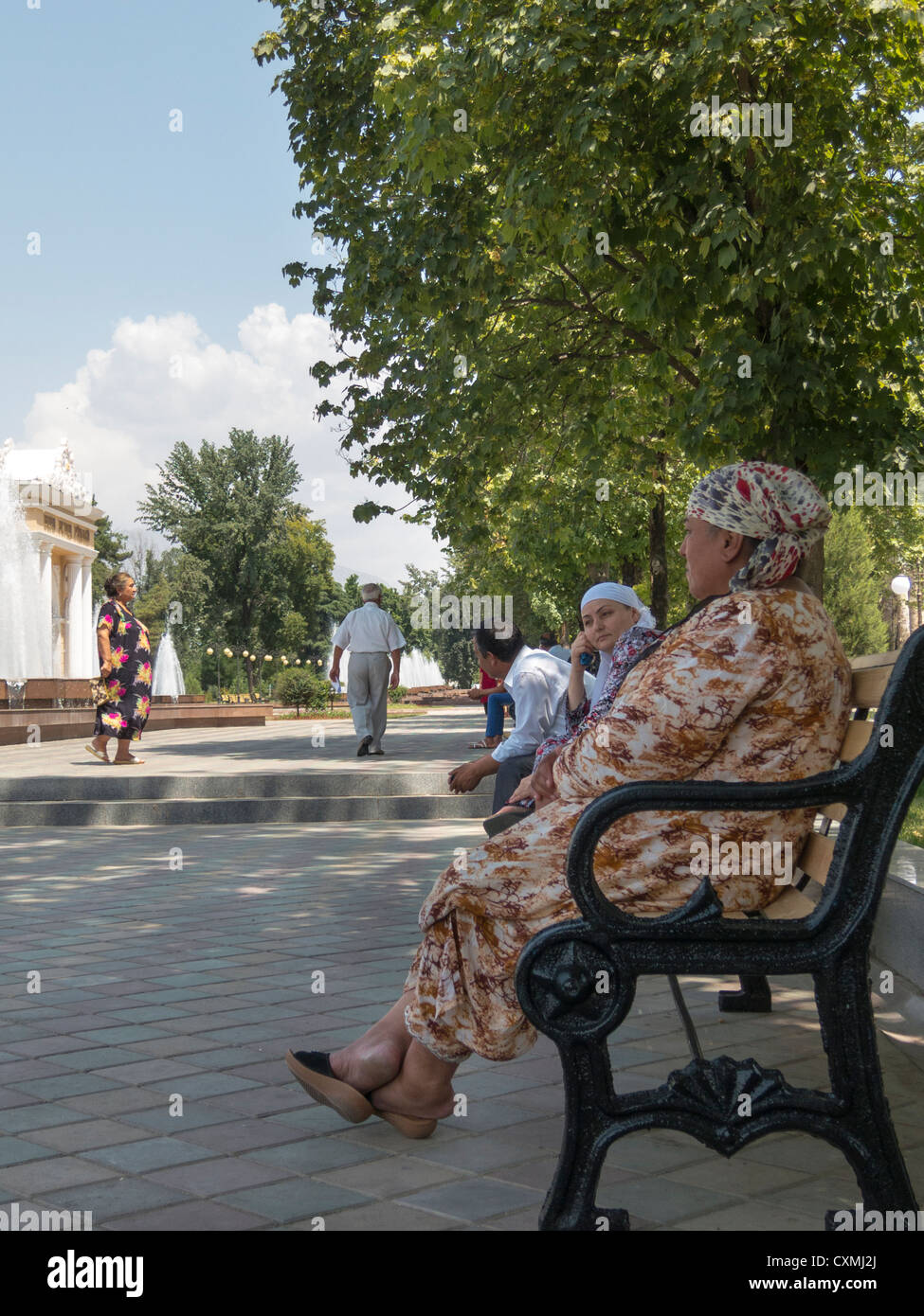 old woman on pavement bench, between Rudaki Street and Central Park, Dushanbe, Tajikistan Stock Photo