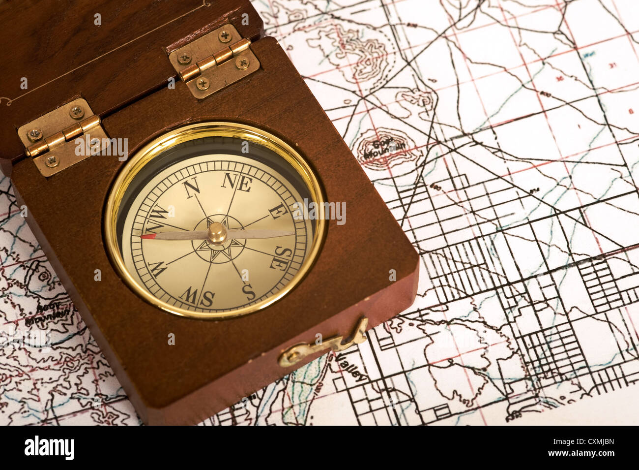 An old wooden compass lying on top of a topographical map Stock Photo